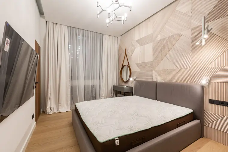Bedroom with laminate flooring, a bed and a wall-mounted television