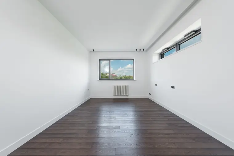 Empty room with white walls and mid-brown laminate flooring