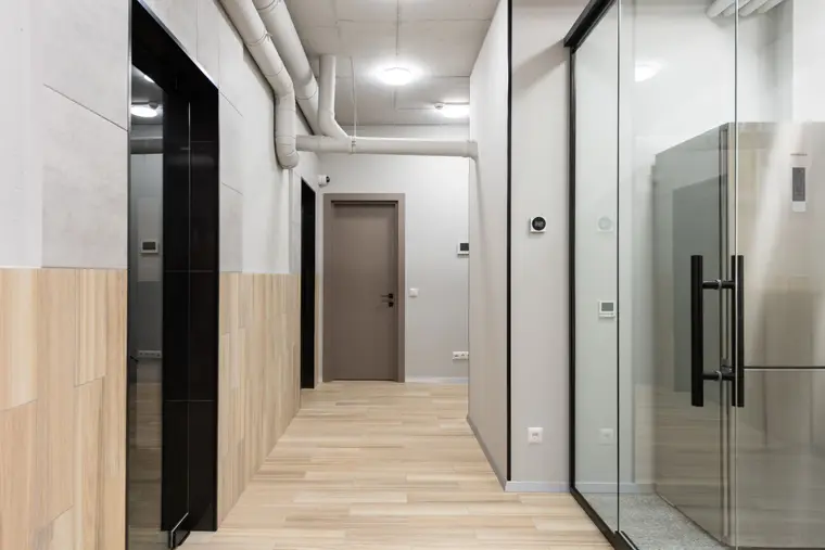 Corridor with parquet-pattern laminate flooring and glazed doors