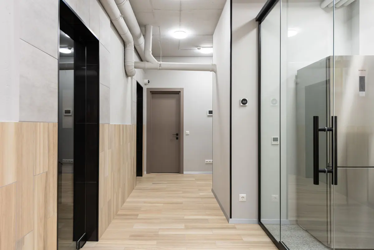 Corridor with parquet-pattern laminate flooring and glazed doors
