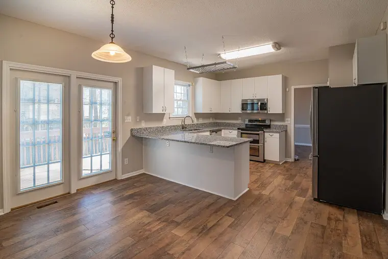 Kitchen with luxury vinyl plank flooring and a stone-topped island