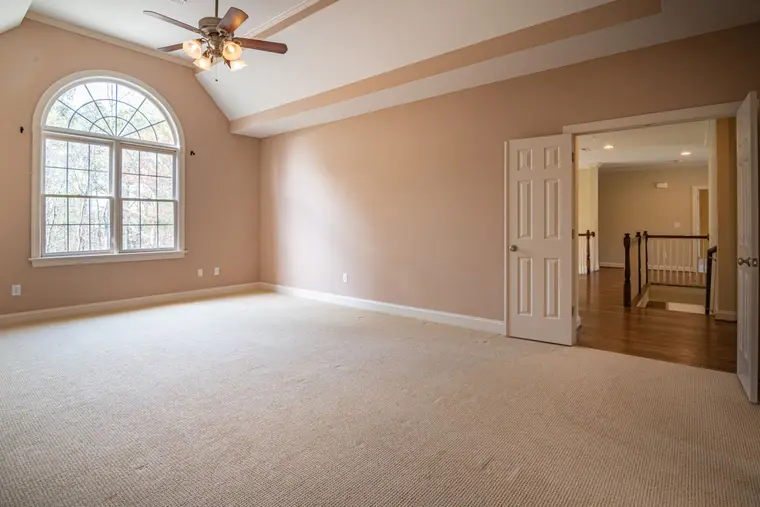 Bright empty room with beige walls and fresh carpet beneath a large window