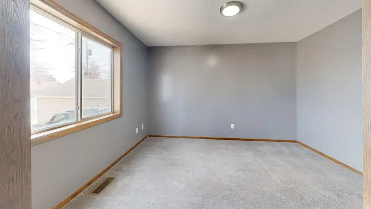 Empty room in neutral tones with new carpet running to the window wall