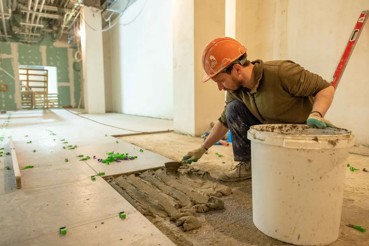 Installer laying tiles over a prepared subfloor