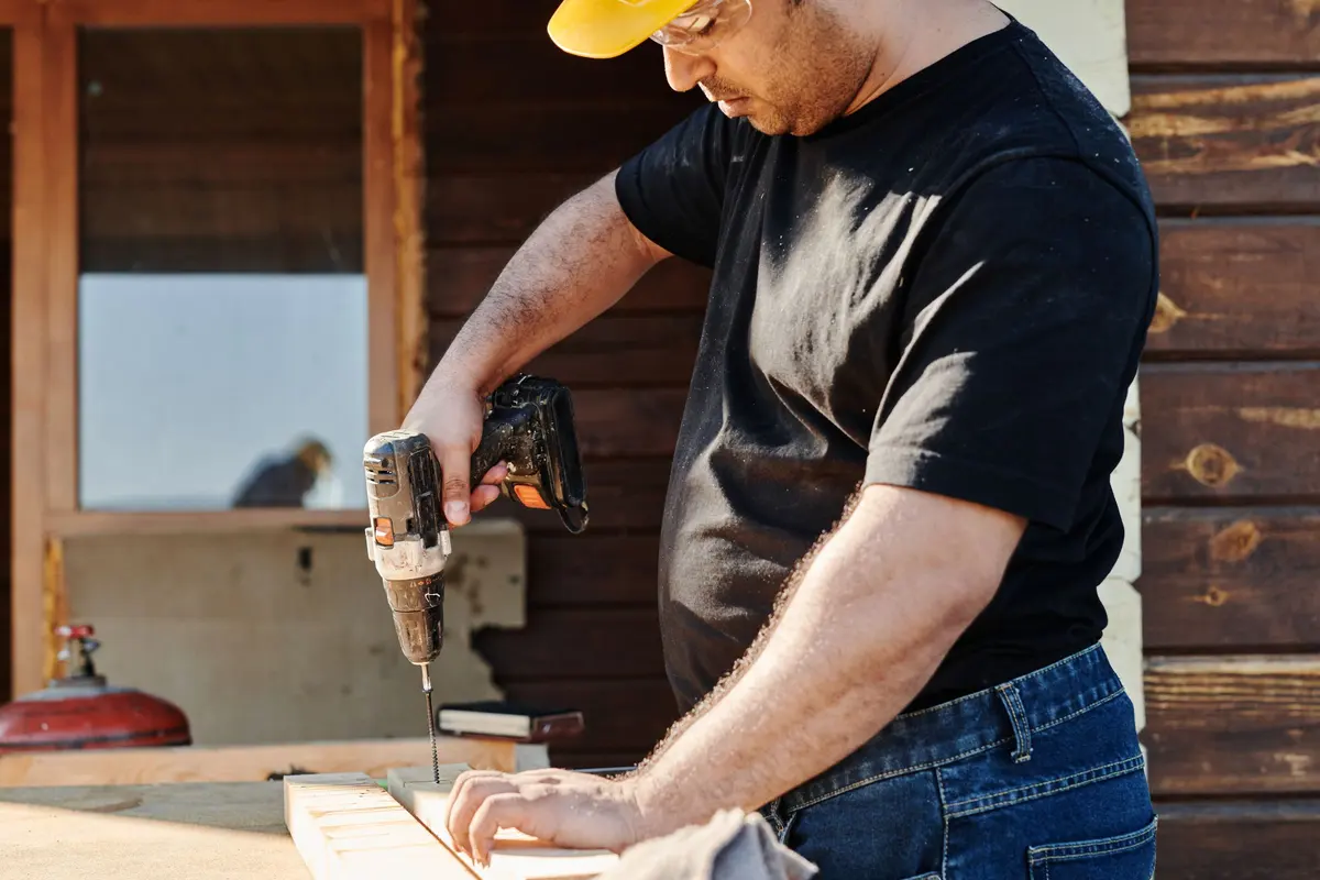 Installer fixing down a subfloor with a power drill