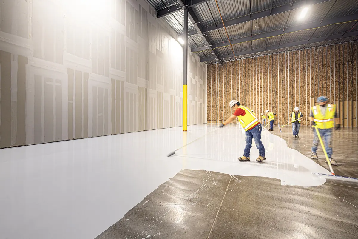 Two installers laying fresh flooring over a prepared subfloor