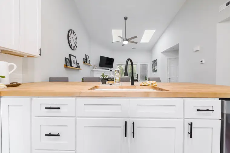 Kitchen with white cabinetry, wood detailing and a stone worktop