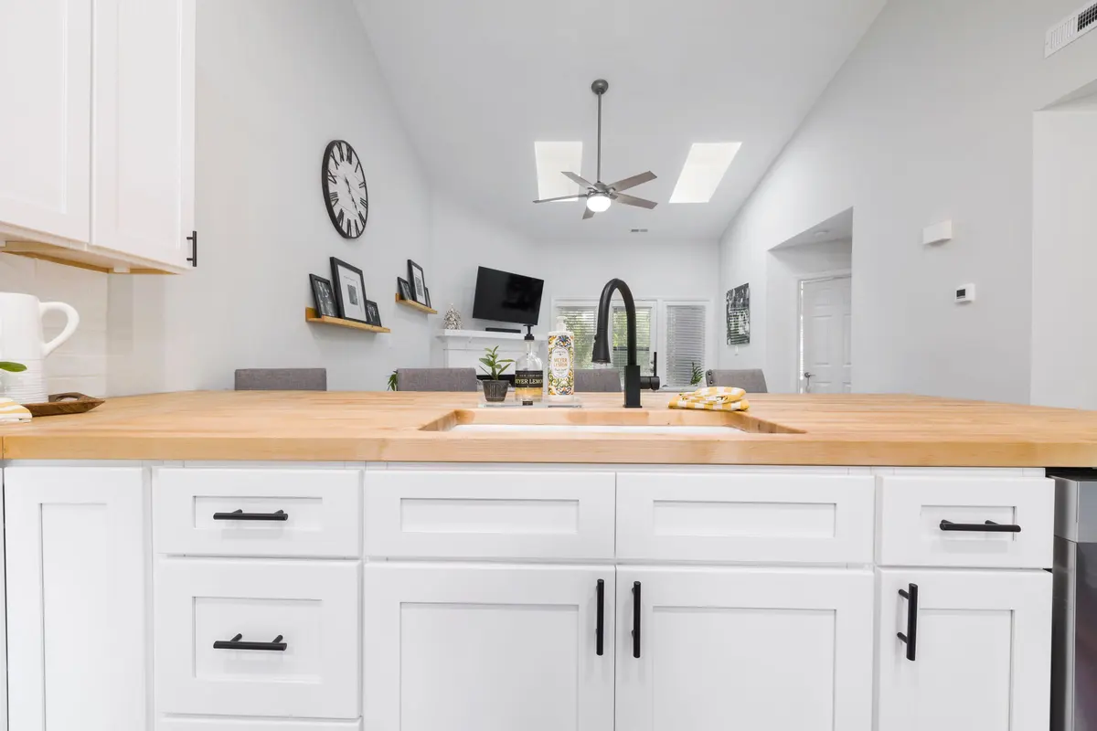 Kitchen with white cabinetry, wood detailing and a stone worktop