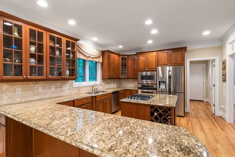 Kitchen with timber cabinets and a full run of stone worktop