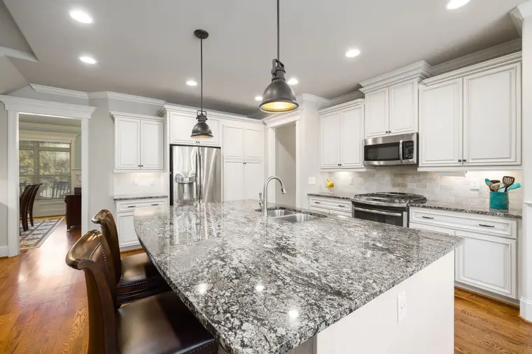 White-cabinet kitchen with a pale stone worktop and breakfast bar
