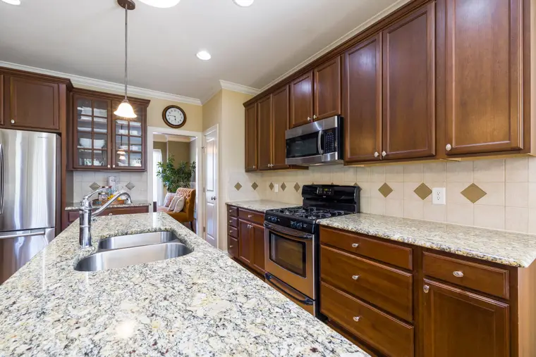 Open kitchen with wood cabinets and a continuous stone counter run