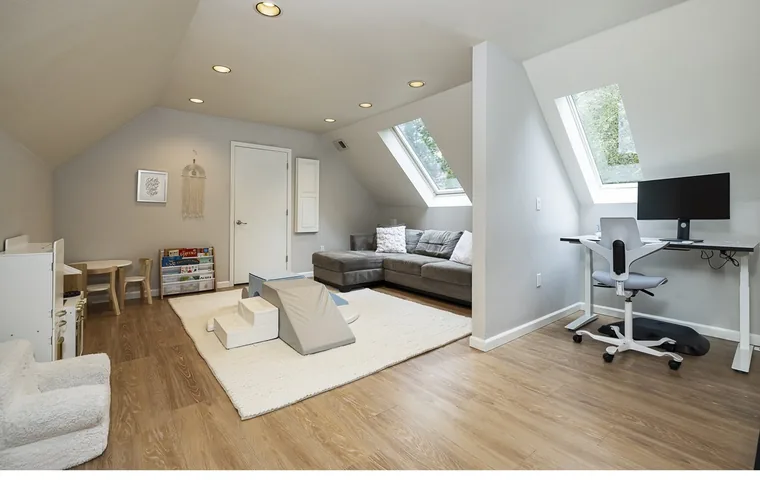 Upstairs bonus room with light wood-look plank flooring under skylights