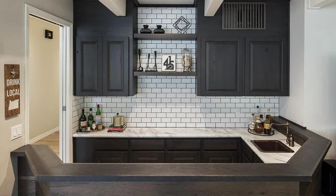 Home bar with a marble counter, subway tile and dark cabinetry