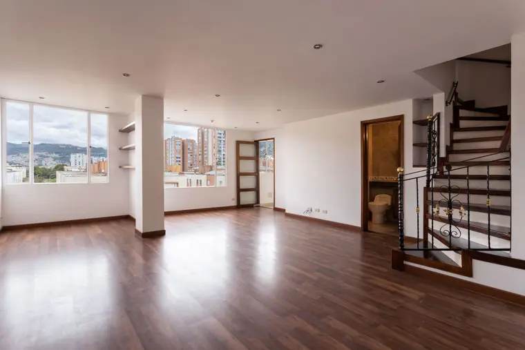 Living room with wood-look flooring running to the stairs
